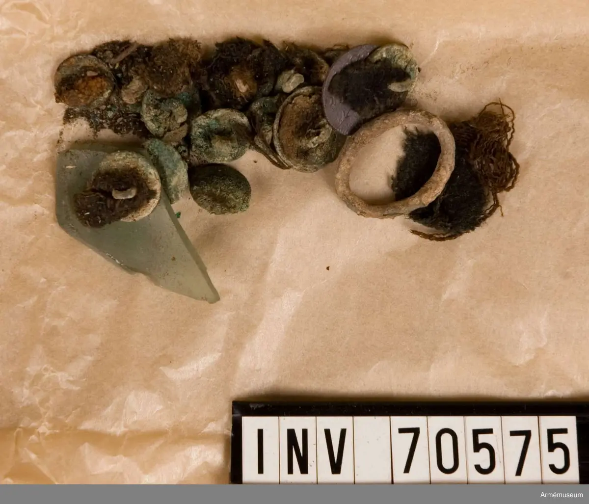 Grupp C:I. 
Funna vid grävningar sommaren 1939. Gravfynd från Sandhamn bestående av knappar och tygrester