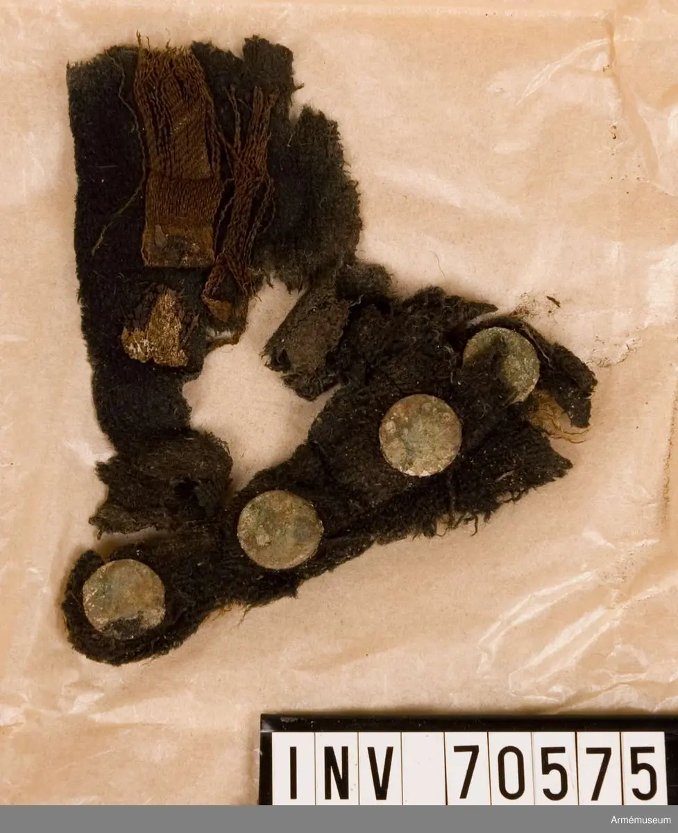 Grupp C:I. 
Funna vid grävningar sommaren 1939. Gravfynd från Sandhamn bestående av knappar och tygrester