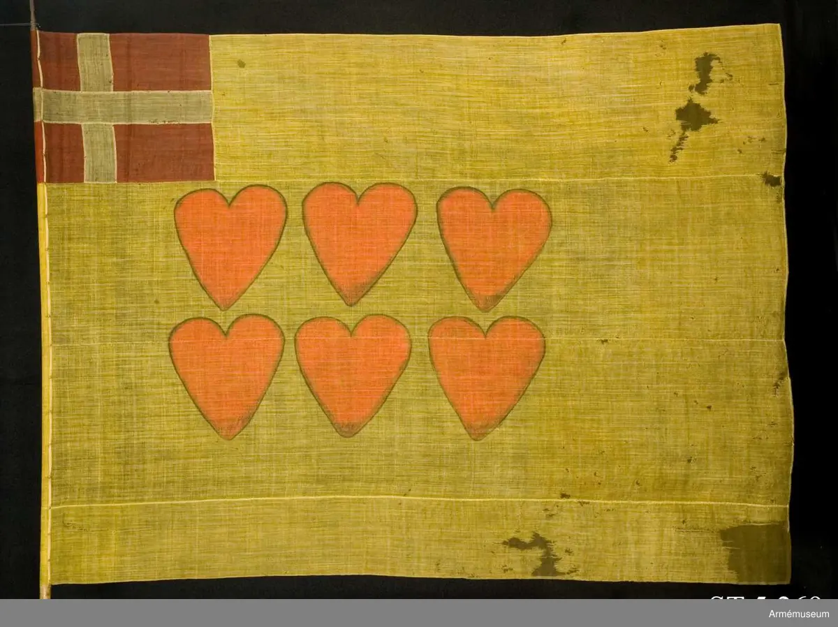 Ylleduk med infällning och målning.

Upptill vid stångsidan infälld Dannebrogen . Mitt på duken målat sex hjärtan i två rader.