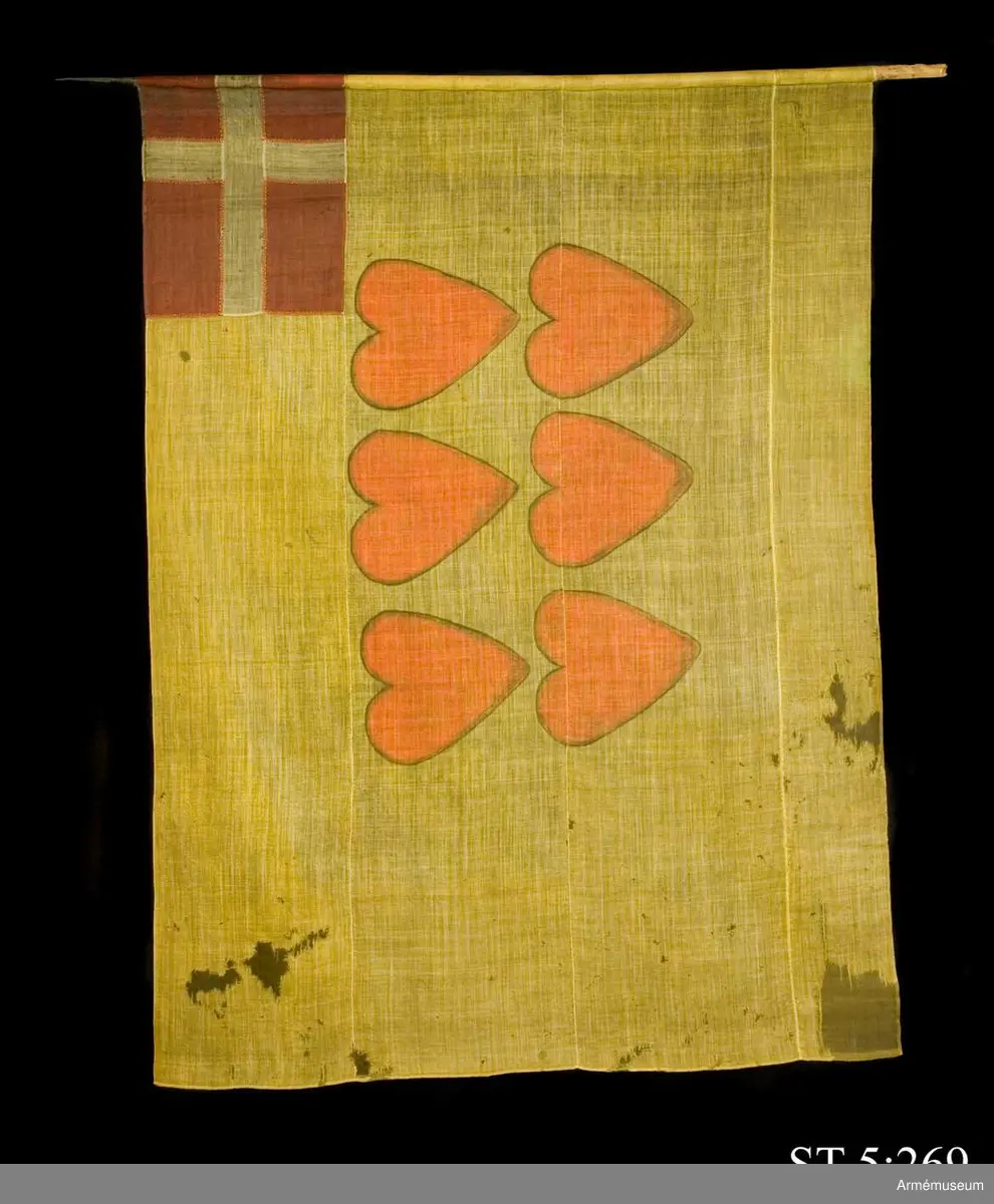 Ylleduk med infällning och målning.

Upptill vid stångsidan infälld Dannebrogen . Mitt på duken målat sex hjärtan i två rader.