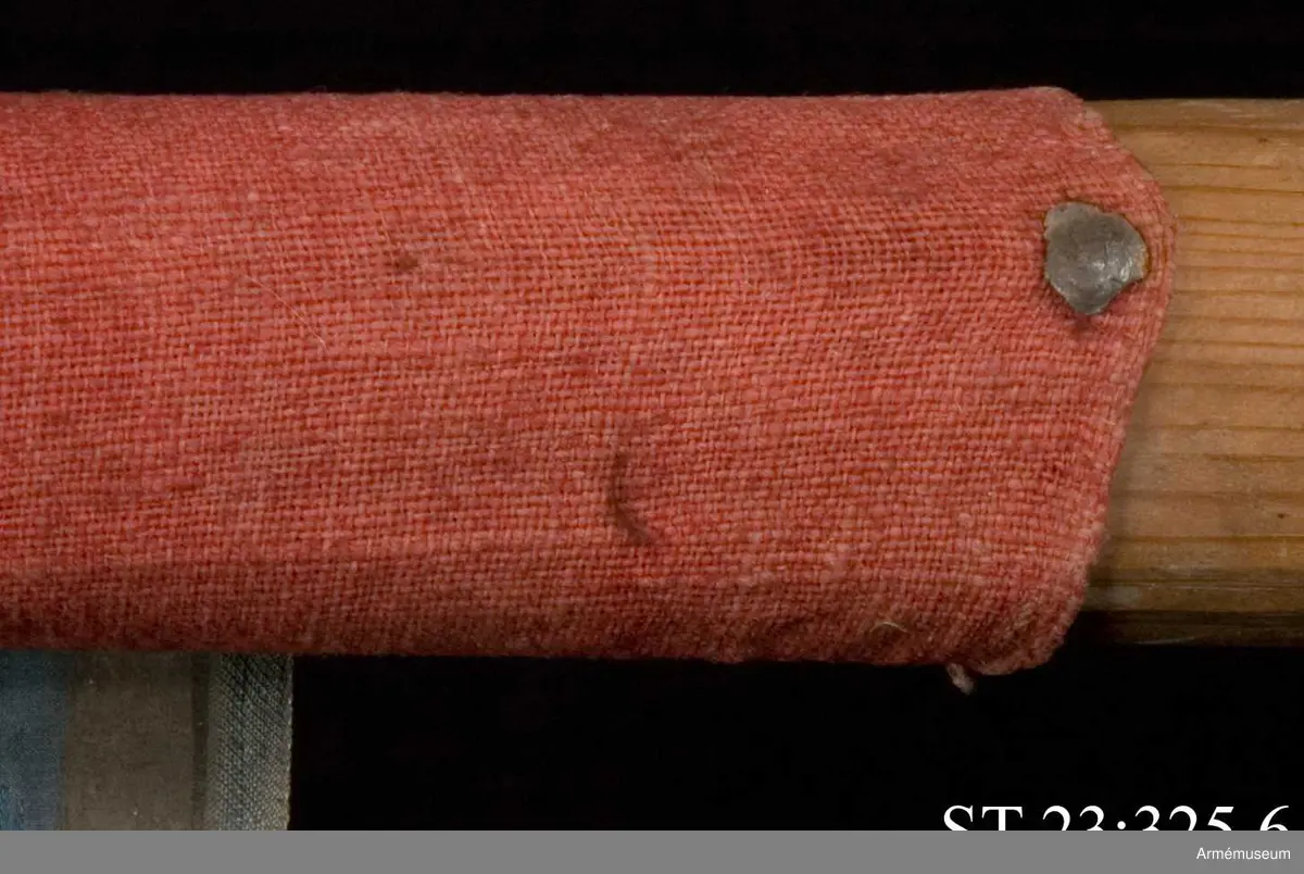 Duk av blå kinesisk sidendamast med målad dekor. Motivet föreställer den romerske kejsaren Konstantins vision av ett kors i skyn kvällen innan slaget vid Pons Mulvius år 312 e Kr mot Maxentius. En ärkeängel med svärd i handen (Gabriel?) svävar över den halshuggne Maxentius. Denna händelse ses som förklaring till att kristna kors började användas på militära fanor. Närmast stångsidan är också ett Golgatakors avbildat. Över detta syns ett moln där Kristus är avbildad. 
Strumpa av rött linne.