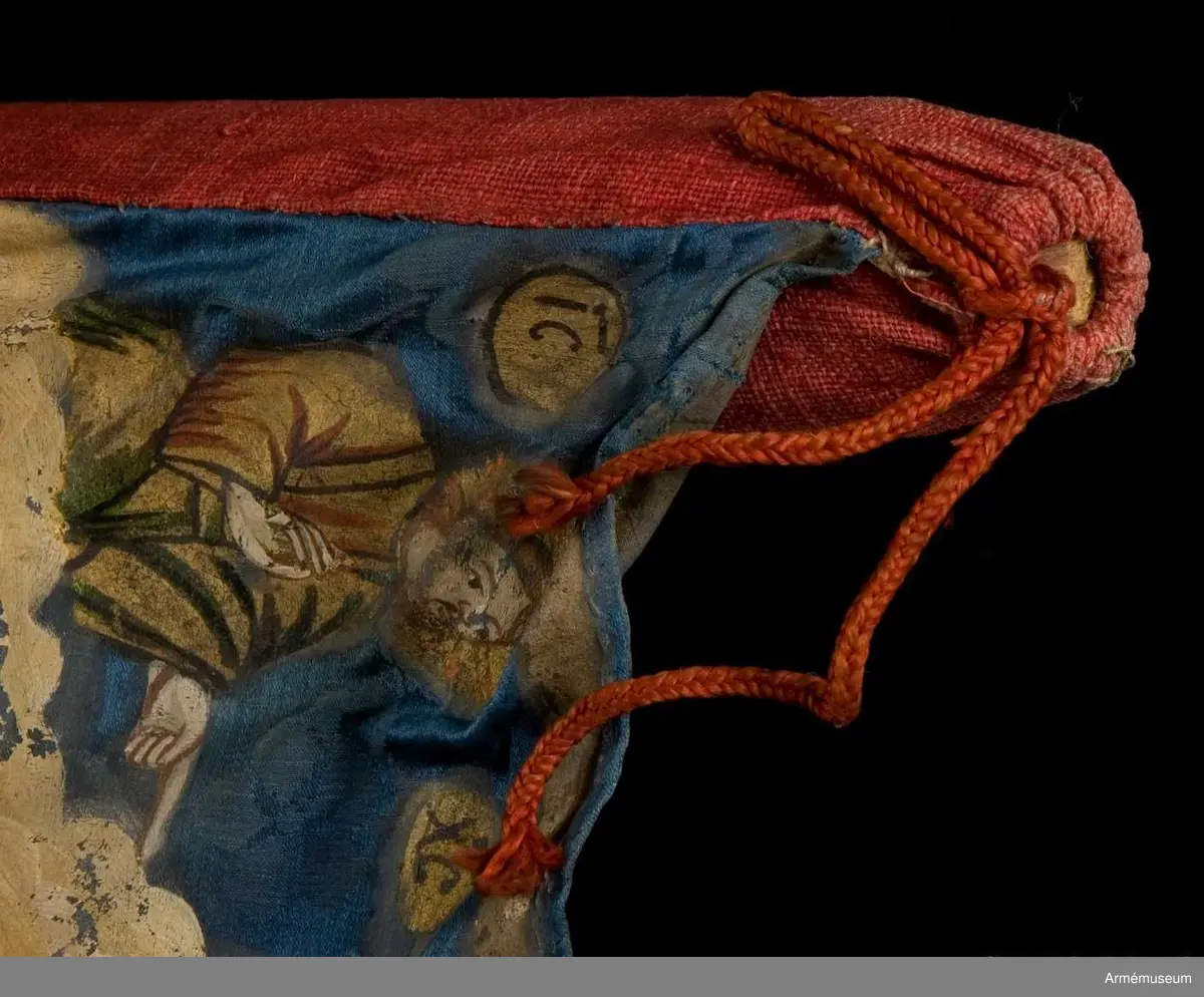 Duk av blå kinesisk sidendamast med målad dekor. Motivet föreställer den romerske kejsaren Konstantins vision av ett kors i skyn kvällen innan slaget vid Pons Mulvius år 312 e Kr mot Maxentius. En ärkeängel med svärd i handen (Gabriel?) svävar över den halshuggne Maxentius. Denna händelse ses som förklaring till att kristna kors började användas på militära fanor. Närmast stångsidan är också ett Golgatakors avbildat. Över detta syns ett moln där Kristus är avbildad. 
Strumpa av rött linne.