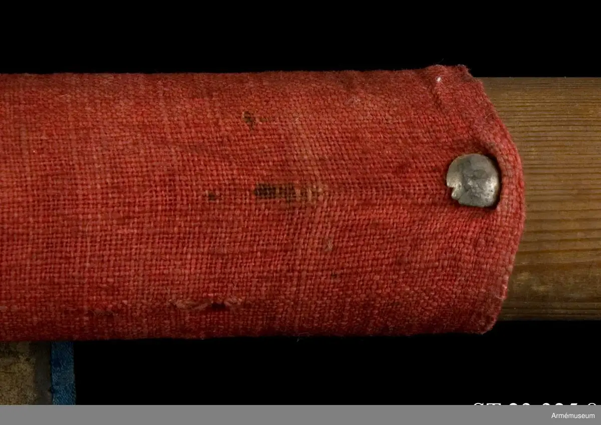 Duk av blå kinesisk sidendamast med målad dekor. Motivet föreställer den romerske kejsaren Konstantins vision av ett kors i skyn kvällen innan slaget vid Pons Mulvius år 312 e Kr mot Maxentius. En ärkeängel med svärd i handen (Gabriel?) svävar över den halshuggne Maxentius. Denna händelse ses som förklaring till att kristna kors började användas på militära fanor. Närmast stångsidan är också ett Golgatakors avbildat. Över detta syns ett moln där Kristus är avbildad. 
Strumpa av rött linne.