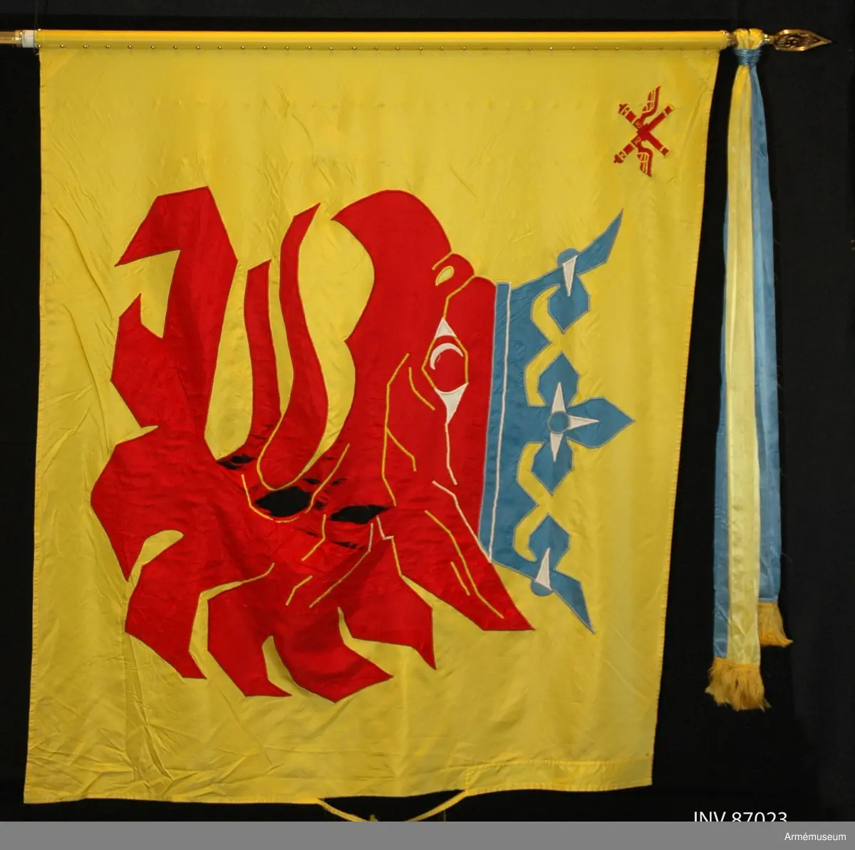 Duk av sidenkypert med landskapet Skånes vapenbild: ett med öppen blå krona krönt avslitet rött griphuvud. I övre inre hörnet två korslagda bevingade röda eldrör av äldre modell. Detta är ett traditionsarv från Skånska luftvärnskåren, Lv4.

Motivet är huvudsakligen utfört i maskinbroderi och intarsia. Vissa detaljer är handbroderade såsom hörnmotivet, näsborren, en del av ögat samt de utskjutande delarna på ömse sidor om kronan. Duken är maskinfållad med sick-sack och raksöm. Triangelformade förstärkningar i övre och nedre stångsidan.

Vitmålad, delbar fanstång. Duken fäst med släta tennlickor. Doppsko av guldfärgad plast, troligen ej ursprunglig. Spets med Carl XVI Gustafs monogram. På holket graverat: "Södra skånska regementet och Södra skånska brigaden 1998".
 
KT 2012-03-06