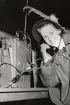 Kvinna lyfter på luren till fälttelefon under uppvisningsdag på Arméns underofficersskola (Försvarets läroverk) i Uppsala 1949.