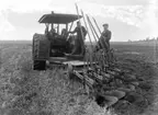 Plöjning vid Nyckelby gård, Övergrans socken, Uppland, 18 maj 1911. Traktorn som syns är enligt uppgift en av de allra första sålda i Sverige.