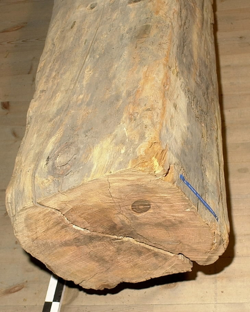 Mastkärna.
Kvadratiskt tvärsnitt. Avsågad/tillputsad i nedre delen efter bärgningen. Andra änden, toppen, är kilformad och spetsigt huggen med liten läpp längs ena sidan. 4 spår för mastjärn utmed långkanterna. Rostfläckar i spåren. Ett urtag på mitten av föremålet. Sprucken. Omkring 30 bulthål. Märkt med blå dymotejp.
Vriden efter bärgning.