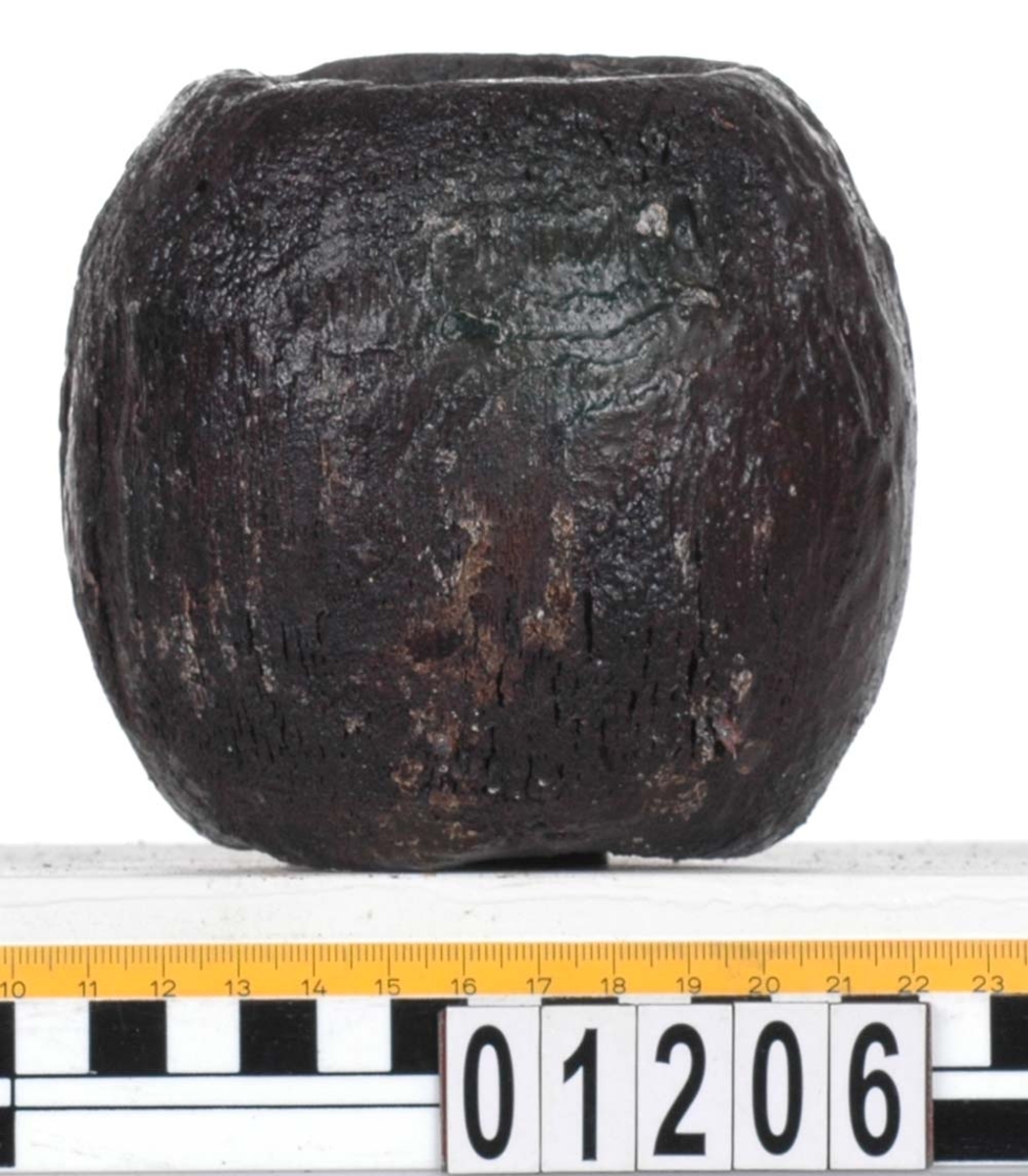 Rackklot. Runt svarvat klot med ett borrat genomgående hål. Saknar fyndbricka men har 2 st. plastmärken och 6 spikar. Eroderat, skador kring hålen.