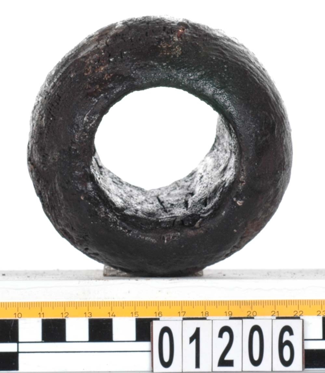 Rackklot. Runt svarvat klot med ett borrat genomgående hål. Saknar fyndbricka men har 2 st. plastmärken och 6 spikar. Eroderat, skador kring hålen.