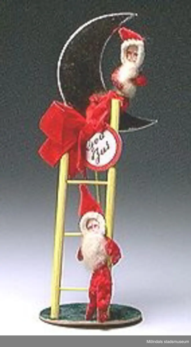 Sex tomtefigurer, tillverkade av flörtkulor kottar och piprensare, en figur består av en stege med två tomtar och en måne.Ingår i Holtermanska samlingen.Märkta med Mm 2859-1-6.