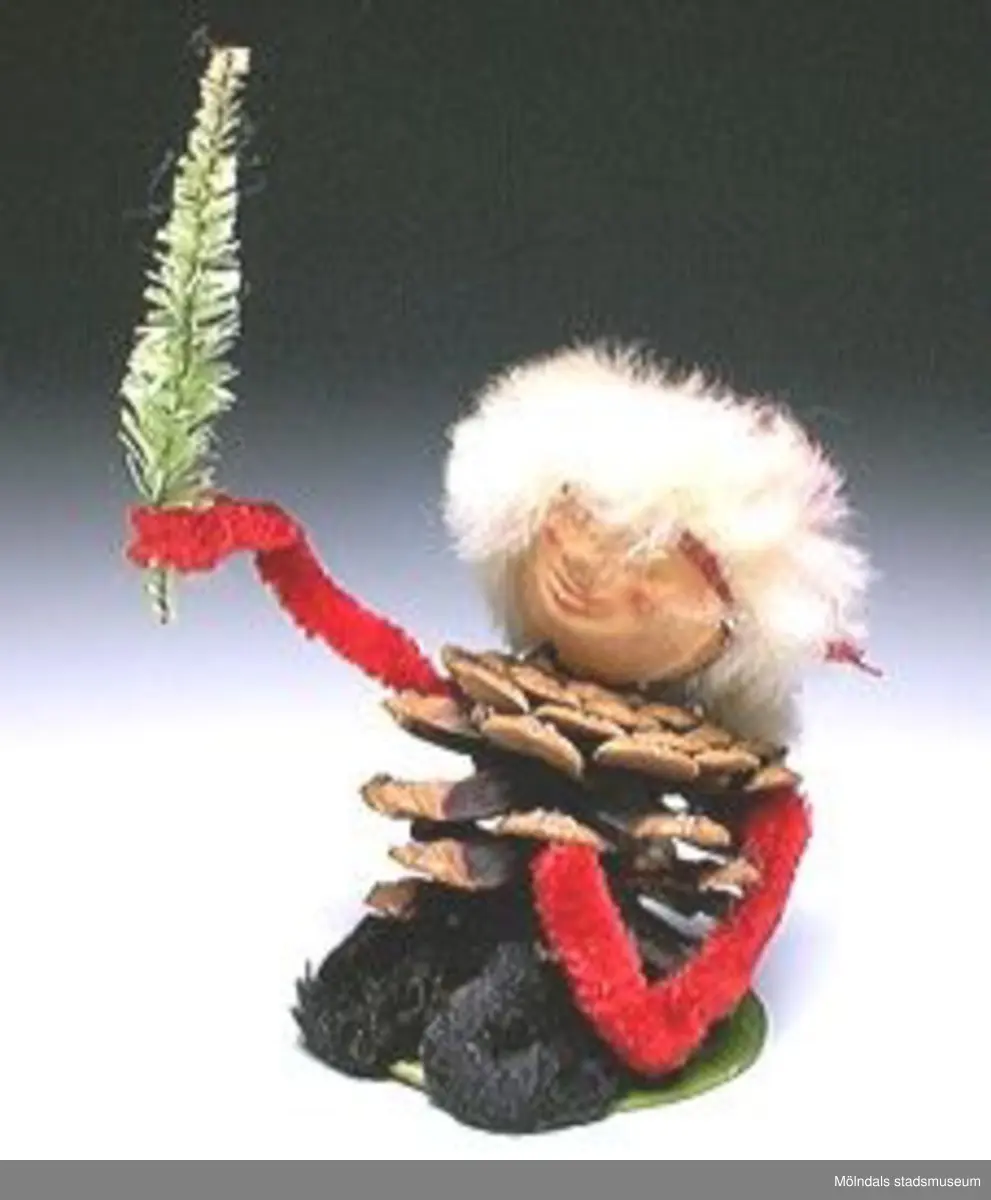 Sex tomtefigurer, tillverkade av flörtkulor kottar och piprensare, en figur består av en stege med två tomtar och en måne.Ingår i Holtermanska samlingen.Märkta med Mm 2859-1-6.