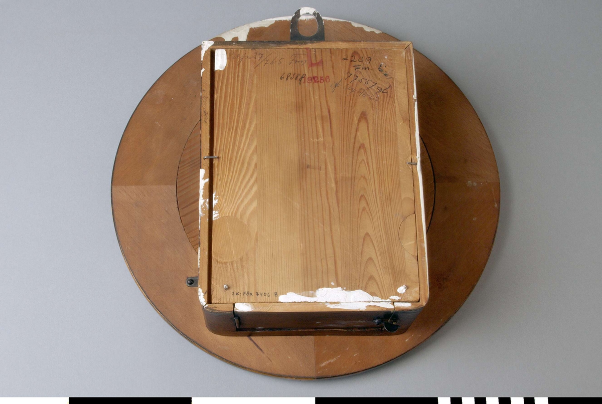 Väggur A, med löstagbar baksida B, och pendel C.
Rund urtavla med arabiska siffror och rund ram. Två visare, ett hål för uppdragning och en åttauddig stjärna med ett J och "UNGHANS" inuti. 
Urverket sitter i en låda av trä skruvad mot urtavlan. Lådan med två runda glasfönster, ett på var sida, och en nedfällbar botten. Det är märkt med samma stjärna som urtavlan och texten: WURTTEMBERG, B 25, 168. Upphängning i lådans översida. 
Anteckningar: Rep 27/765 Frej (? svårläsligt), 2209 Fm, 68 38 R, 77557 gb, gb rep 5/6-62. En stämpel i rött: L 18256.