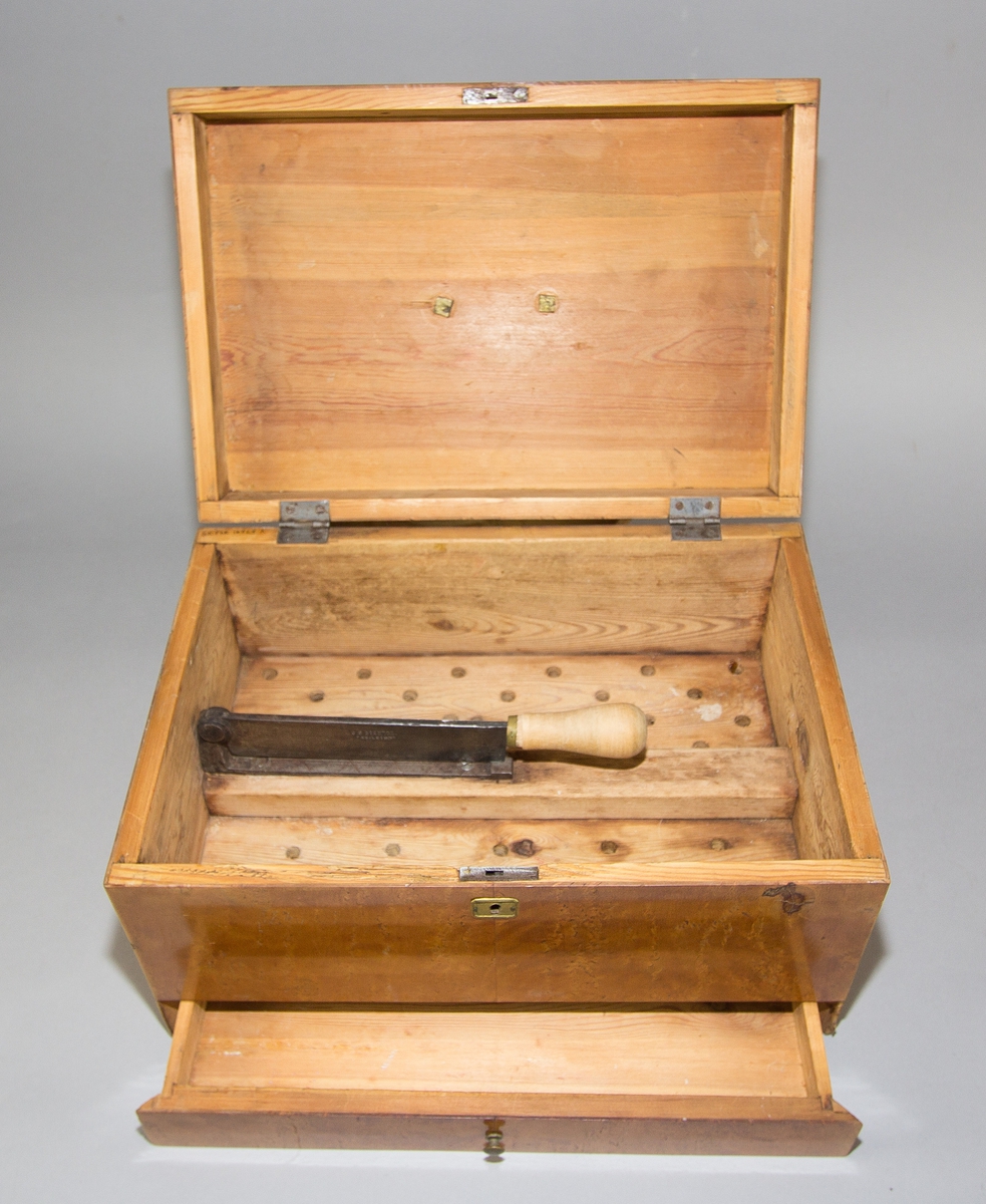 Sockerskrin (A) med lock av masurfanerat trä. Nyckelskylt och handtag av mässing. Låda (B) nertill med knopp av mässing. Skrin och låda med sinkade fogar. Locket på två gångjärn av järn. Invändigt en fast hackkniv med gångjärn av järn med svarvat handtag av trä med mässingsring. Kniven skruvad på tvärgående mellanvägg vilandes på en perforerad innerbotten. 
Med nyckel (C).