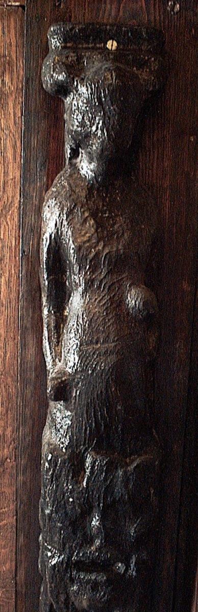 Skulpterad pilaster utformad som en karyatid med långt hår, troligen placerad under ett joniskt kapitäl.
Huvudet är vridet åt vänster. Höger arm är sträckt utefter sidan. Vänster arm är böjd och i handen håller figuren ett okänt föremål.
Pilasterskaftet är upptill prytt med en maskaron med bred, öppen mun och nedtill med en tung fruktfeston. Det nedåt avsmalnande pilasterskaftet avgränsas från piedestalen av en enkel vulst eller list med uppdragna kanter. Piedestalen är hög och jämnbred samt prydd med ett litet huvud och avslutas nedtill med en förtjockad bas. Skulpturens baksida är slät.
Skulpturen är kraftigt sliten och nött med finare detaljer utplånade.

Text in English: Sculpted pilaster with Caryatid with long hair under what is possibly an Ionic capital.
The head is turned to the left, the right arm is streched along the side, the left arm is bent and the hand holds an unknown object.
The shaft of the pilaster is decorated above with a mask with a broad, open mouth, below is a heavy festoon of fruit. The shaft tapers downwards and is divided from its pedestal by a simple torus or batten with drawn-up edges. The pedestal is high and even in width and decorated with a small head. It terminates at the bottom in a thickened base. Its back is smooth.
The sculpture is much worn, with finer details obliterated.