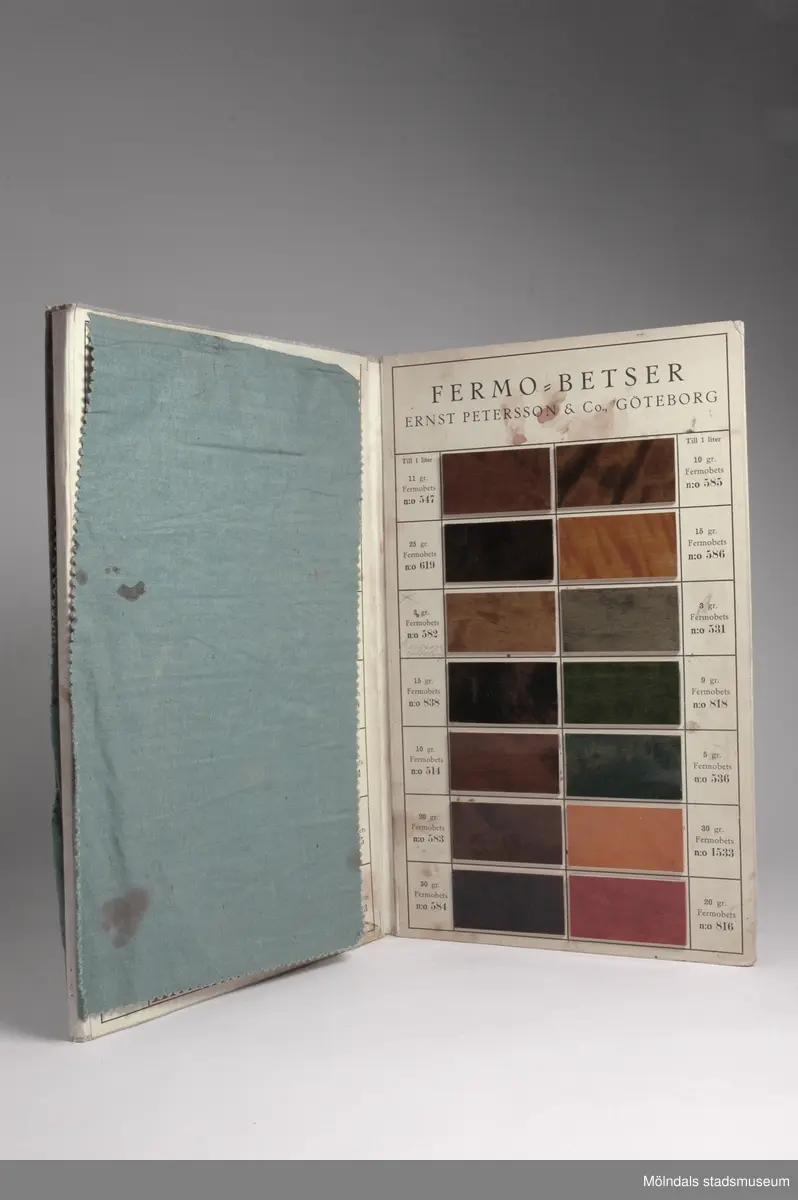 Provkarta med möbelträbetsfärger.Redskap och verktyg kommer från Lindströms snickeri (Gamla Riksvägen 81, Ekebacken). Här byggde John Lindström från Lindome ett boningshus och snickeriverkstad 1928. Han öppnade ett snickeri som specialiserade sig på köksbord Borden levererades till en grossist i Göteborg. Som mest tillverkades 50-60 bord i veckan. Borden hade ben av björk och resten var av furu. Han gjorde även andra möbler på beställning. Till hjälp hade John ett par anställda.De sista åren gjordes mest renoveringar och reparationer, medan det "begav sig" de mest aktiva åren tillverkades bord av alla de slag.