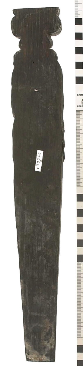 Hermpilaster.

Liten pilaster i form av en karyatid, med långt böljande hår under joniskt kapitäl.

Huvudet är vridet en aning åt höger. Med vänster hand hålls manteln samlad. I höger hand håller figuren en frukt eller dylikt framför bröstet. Pilasterskaftet är prytt med stora frukter och blad, fasthängande vid en stängel som delvis täcker det nedåt avsmalnande skaftets ramverk. Baksidan är slät.

Skulpturen är välbevarad, förutom ansiktet som är kraftigt slitet.

Fyra stycken spikhål, en övertäckt med en plugg.


Text in English: Sculpted small pilaster with a Caryatid with long wavy hair beneath an Ionic capital.

Its head is turned slightly to the right, its left hand holds its gathered mantle. Its right hand holds fruit or the like in front of its brests. The shaft of the pilaster is decorated with fruit and large leaves hanging from a stalk, which partly cover the framing of the tapering shaft. Its back is flat.

The sculpture is somewhat worn, its facial expression has been obliterated.
