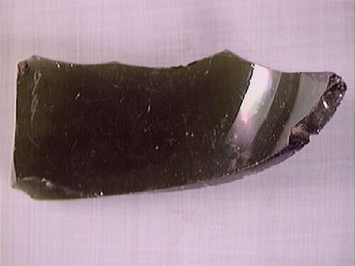 En flaskhals samt en glasskärva.  Flaskhalsen är brunfärgad. Vid flaskmynning ligger glassträngen omlott. Glasbiten är grönfärgad. Troligtvis rör det sig om skärva från flaskans buk. Flaskhalsen och glasskärvan härrör från två olika flaskor.

09262a: Finish has laid-on ring, common on bottles before 1850s (https://sha.org/bottle/finishes.htm), finish also has possible mold line, possibly intrusive artifact. Glass is olive color.
09262b: Glass is dark green.