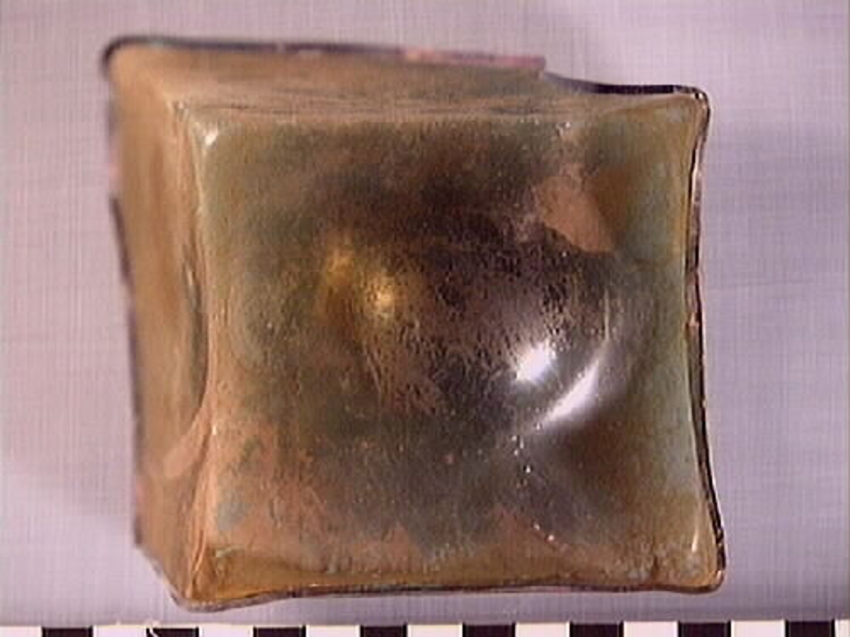 Botten samt fyra skärvor från fyrsidig flaska med stucken botten. På bottnens undersida finns ett puntelmärke. Glaset är grönfärgat och har en iriserande beläggning.

No damage. All pieces are a light green color and are from a case bottle.
10194a: has worn spot
10194c: Consists of two artifact numbers that have been glued together. Artifact has moderate scaling.