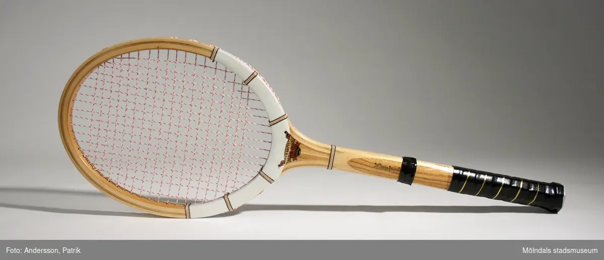 Oanvändt tennisracket från 1970-talet.Racket är av trä. Nedre delen av skaftet är tejpat för att få ett bättre grepp. Skaftet har också målad text på båda sidor: "DIAMOND SUPER" och "A Laminated Construction". I endan av skaftet sitter en plastplugg där texten "MADE IN PAKISTAN" tryckt.MåttNätet: 240 mm x 310 mm, Höjd: 17 mm,  Längd med skaft: 686 mm, Längd på skaft: 377 mm, Diam på skaft: ca. 35mm.  