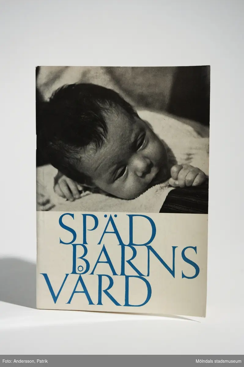 1 st handbok (MM04935:1) - "Spädbarnsvård" (skrift nr 41), utgiven 1964 av Socialmedicinska barnavårdsdelegationen. Författare: Professor Bo Wahlquist. Tryckeri: Eklunds & Vasatryck Förlags AB 1964.I boken ligger också tidningsurklippet (MM04935:2): "VI VILL HA RENA MÄN DYGNET RUNT". Artikeln är ett uppslag ur okänd tidning (2 sidor) med okänt utgivningsår. Men man kan se att artikeln är skriven av Birgit Sunesson.Boken har mjuka pärmar. Framsidan har vit bakgrund med ett svartvitt footografi på ett spädbarn. Under bilden står bokens namn med tryckt blå text.Bokens baksida är vit och har en tecknad bild på ett barn med en nalle. På baksidan står också bokens pris: "Pris 3:-".Boken innehåller tips & råd kring mödra- och barnavård och uppfostringsfrågor, barnets mat, kläder och leksaker med mera.Omslag, teckningar och Layout: Märtha PeterssonOmslagsfotografi: Kerstin JacobMåttHandbok (MM04935:1), Längd: 209 mm, Bredd: 147 mm, Höjd: cirka 3 mmArtikel (MM04935:2), Längd: 294 mm, Bredd: 221 mm