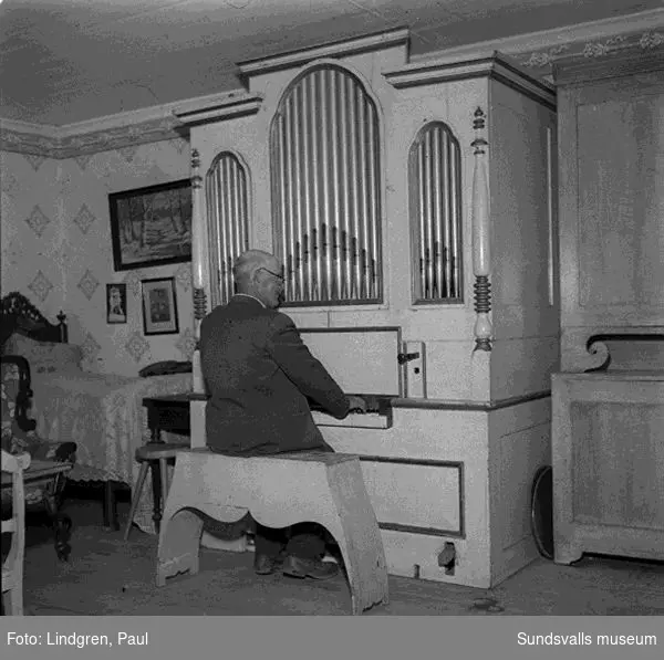 Bostad, museum? exteriör, interiör, man visar träsniderier, spelar orgel.