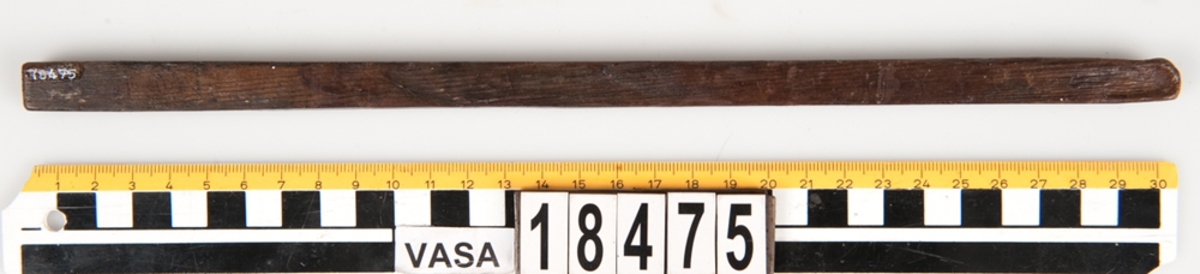 En tumstock av trä.

Tumstocken är försedd med elva inristade skåror som markerar tolv tum. På den mittersta skåran finns ett inristat kryss. Ytterligare ett kryss, dock något mindre, har ristats in vid skåran närmast mittskåran.

Tumstocken är i gott skick.

För mer information se Dokumentationsblankett under Referenser – Länkade filer.