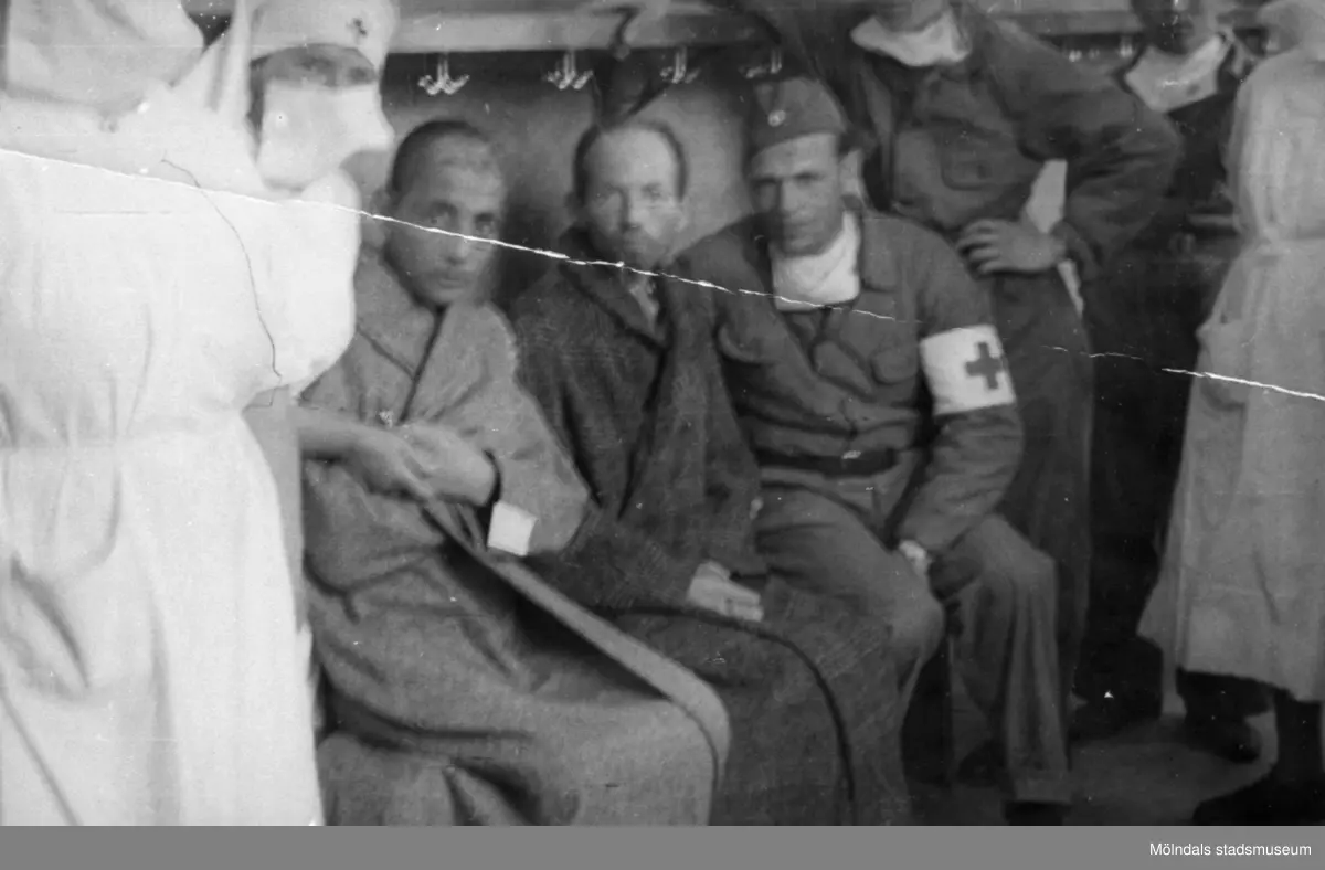 "Karantänsförläggning" på Kvarnbyskolan för överlevande från koncentrationsläger i Tyskland och Polen 1945.  
Skolan fungerade under denna sommar som beredsskapssjukhus.

Två manliga patienter omgivna av Röda Kors personal.
