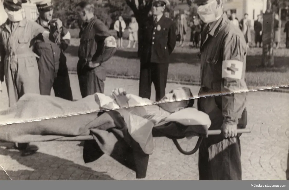 "Karantänsförläggning" på Kvarnbyskolan för överlevande från koncentrationsläger i Tyskland och Polen 1945.  
Skolan fungerade under denna sommar som beredsskapssjukhus.
 
Flykting som blir buren på bår av Röda Korsets personal.