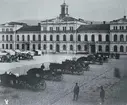 Bilden visar Stadshuset före stadsbranden 1888. Framför Stadshuset Stora torget med torghandel och ett antal droskor med kuskar.
Bildtext på vykortet 