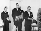 Uppvaktning å postsparbankschefens Sven Lönnqvist tjänsterum.  Foto
10/3 1959.  Finska postsparbanken uppvaktar. Fr.v. fru Vanhala,
postdirektör Vanhala och generaldirektör Aura, i bakgrunden
postdirektör Saloila.