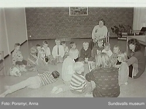 Dokumentationsfotografering av verksamheten vid biblioteksfilialen i Matfors. Bild 01Biblioteksassistenten Ingrid Engström, Matfors bibliotek, med låntagare vid utlånedisken. Bild 09 bibliotekaren Inger Barkman läser för en grupp förskolebarn i bibliotekets "läsrum".