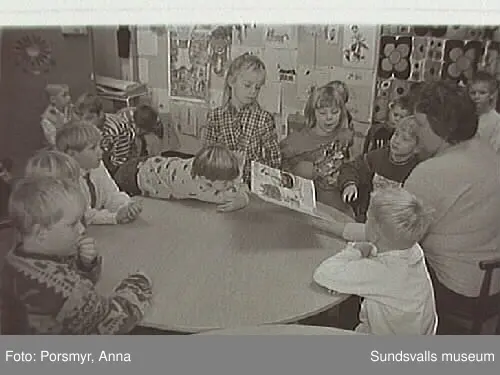 Dokumentationsfotografering av verksamheten vid biblioteksfilialen i Matfors. Bild 01Biblioteksassistenten Ingrid Engström, Matfors bibliotek, med låntagare vid utlånedisken. Bild 09 bibliotekaren Inger Barkman läser för en grupp förskolebarn i bibliotekets "läsrum".