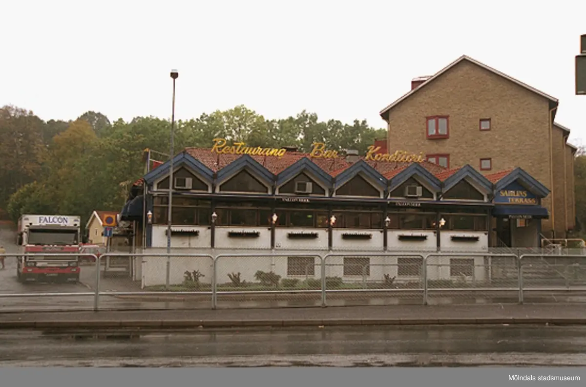 Sahlins terrass på Storgatan/Frölundagatan. Mölndalsbro i dag - ett skolpedagogiskt dokumentationsprojekt på Mölndals museum under oktober 1996. 1996_1135-1152 är gjorda av högstadieelever från Kvarnbyskolan 9D, grupp 1. Se även 1996_0913-0940, gruppbilder på klasserna 1996_1382-1405 samt bilder från den färdiga utställningen 1996_1358-1381.