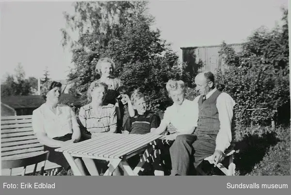 Fr.v. Sigrid Ödlund, Siri Edblad och Irma Edblad, okänd, Tord Ödlund, Stina Cramby och Hilding Ödlund i familjen Edblads trädgård, Södermalmsgatan 8, där familjen bodde 1939 - 1960. Sigrid Ödlund var moster och Stina Cramby syster till Siri Edblad. Fastigheten ägdes av Helfrid Renström, som bodde i husets undervåning.