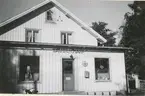 Exteriör av poststationen i Hackvad, inrymd i en butik, 1954.