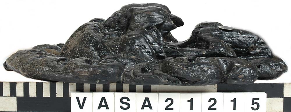 Skulpturdel som tillsammans med del 10955 utgör vänster halva av en lejonmaskaron. I sin helhet är lejonmaskaronen rektangulär till formen och utförd i ursprungligen två sektioner. Ansiktet har stora, runda ögon och kraftiga ögonbrynsbågar. Nosen är platt och bred och klart avgränsad från den rundade överkäken. Det vidöppna gapet har breda, något inåtsvängda tänder och en bred tunga. Underkäken är försedd med två strutformade hårtofsar. Lejonets man är i det närmaste jämnbred och kraftig.

Skulpturen är relativt välbevarad, dock något nött. Del 10955 är avsprucken från sektion 21215 och del 10956 är avsprucken från sektion 21218. Tillsammans utgör de fyra delarna en hel maskaron.



Text in English: Part of a sculpture: left half of a lion mask. The mask is I SIN HELHET rectangular in form and made in two sections. The lion''s face has large round eyes and powerful eyebrows. The flat broad nose is clearly separated from the rounded upper jaw. The jaws are wide open with broad and somewhat concave teeth and a broad tongue. The lower jaw has two cone-shaped tufts of hair. The lion''s mane is powerful and almost of even width.

The sculpture is largely well preserved although rather worn.