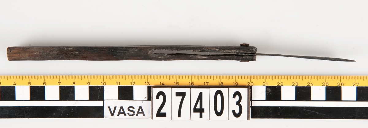 En vinkelhake, s k smygvinkel.

Skaftet är försett med sex stycken ristade skåror som markerar tum. I ena skaftänden sitter ett nytillverkat, ledat, järnblad. Bladet är fäst med en nytillverkad järnsplint. I skaftets ena ände, närmast bladet, löper en skåra eller ett spår. Spåret är mellan 68 och 80 mm djupt.

Smygvinkeln är i gott skick.

För mer information se Dokumentationsblankett under Referenser – Länkade filer.