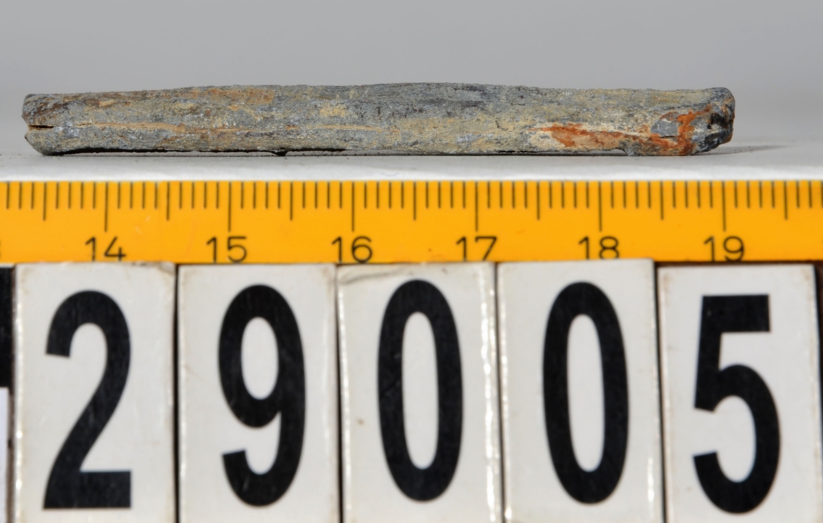 Sänket består av en vikt blybit. Sänket har tydliga märken efter det verktyg som pressat ihop sänket runt garntråden. Sänket är i gott skick.

Text in English: Lead sinker in the shape of a flat tube. The rectangular piece of lead is folded vertically in half and has visible tool marks from the folding process. The yarn is pushed through the hole. Grey mat in colour. In good condition.