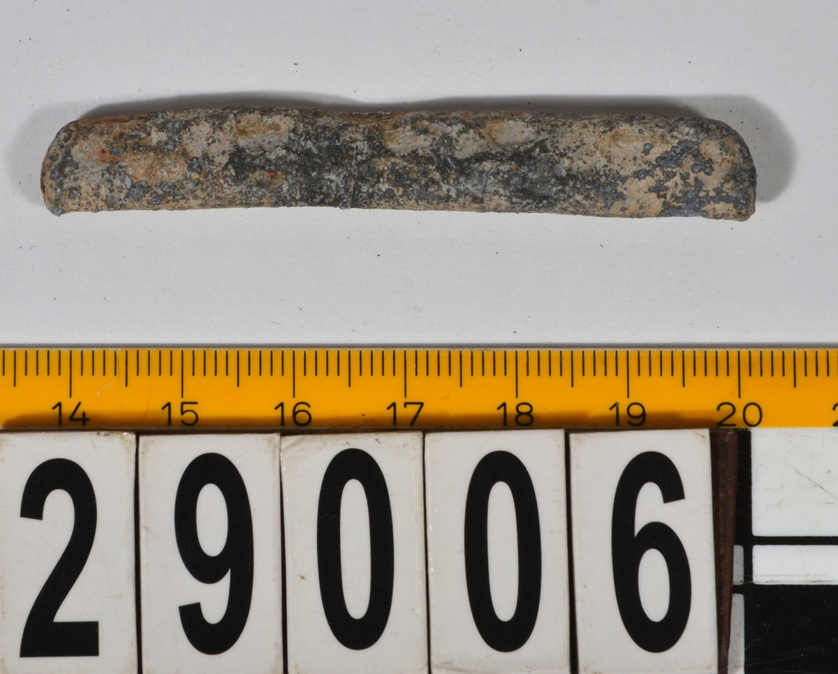 Sänket består av vikt blybit. Sänket har tydliga märken efter det verktyg som pressat ihop sänket runt garntråden. Sänket är i gott skick.

Text in English: Lead sinker in the shape of a flat tube. The rectangular piece of lead is folded vertically in half and has visible tool marks from the folding process. The yarn is pushed through the hole. Grey mat in colour. In good condition.