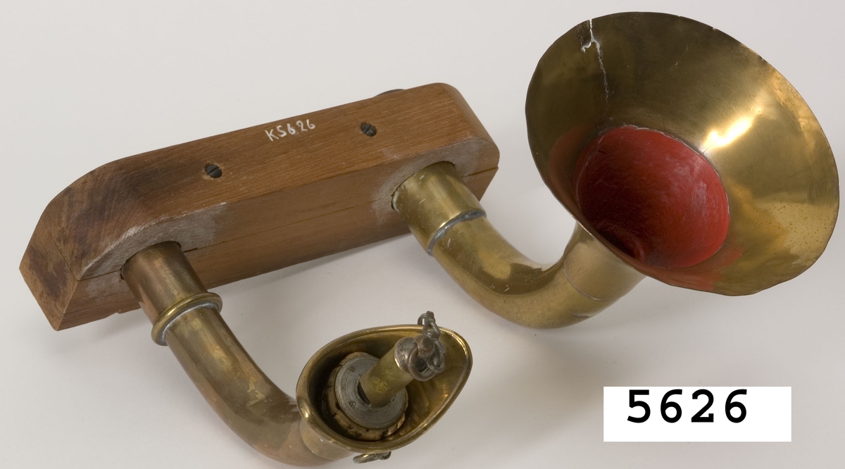 Talrör bestående av två st. mässingsrör, bågformade. Det ena röret, som är avsett för inkommande samtal är i yttre änden ovalformat och försett med en lös visselpipa med propp av kork. Det andra röret, taltratten är i yttre änden trattformat. Rören är fastsatta på en platta av trä.