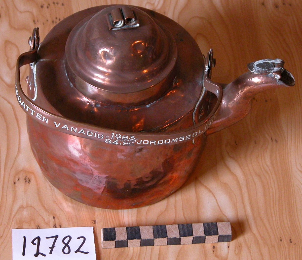 Kaffekittel av koppar med grepe och pip.

Märkning på grepen: Fregatten Vanadis jordenruntsegling 1883, 84,85. C.A. Bayard.