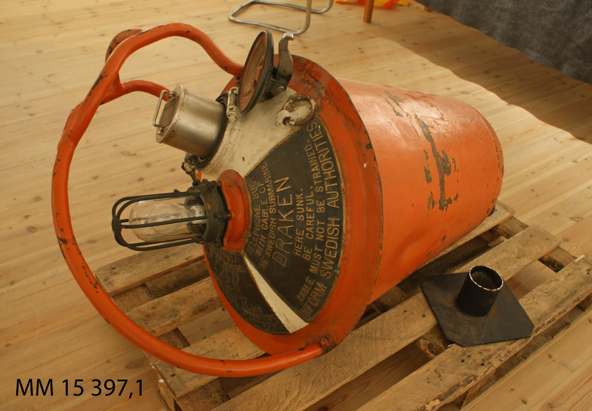 Telefonboj, rödfärgad, konformig  metallboj med stålbygel och vitfärgad överdel. Överdelen består av en lampa med skyddsnät och intill denna en behållare  med diametern 130 mm med tätslutande lock i vilken en telefontub ligger placerad (se MM 15357.2). På bojens överdel sitter två skyltar med svensk och engelsk text fastgjorda.
Skylt 1: "Telefonboj med telefonkabel till U-båten Draken som har sjunkit. Iakttag varsamhet så att kabeln ej utsättes för påfrestning. Underrätta Myndigheterna".
Skylt 2: "Telephone Buoy with cable of the Swedish submarine Draken, here sunk.  Be careful, cable must not be strained. Inform Swedish Authorities".