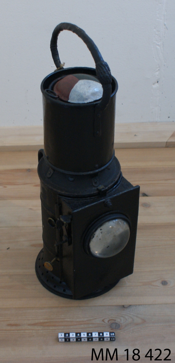 Signallanterna av koppar, målad svart, för fotogen. Cylindrisk form. Framsida låda med rund lins, bakom vilken en plåtskiva sitter, reglerbar med en fjäder. Inuti lanternan finns en fotogenlampa med oljehus, brännare och reflektorspegel, lampglas saknas. Lanternans överdel är försedd med två konvexa lampglas, ett rött och ett blått, samt en öppning utan glas. Överst finns målad symbol i färger vit, svart och röd så att glasen kan vridas i rätt läge. Bak på lanternan sitter bygelhandtag, samt överst ett runt handtag.
Vidhängande lapp: "Thetis"