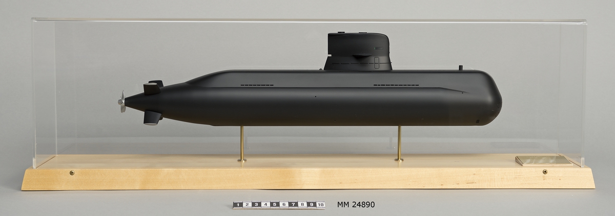 Ubåtsmodell Gotland i monter. Modell av alträ med detaljer av mässing, målad med cellulosafärg. Svart skrov. Monter av plexiglas på träplatta. Mässingsbricka i montern med uppgifter om modellen.