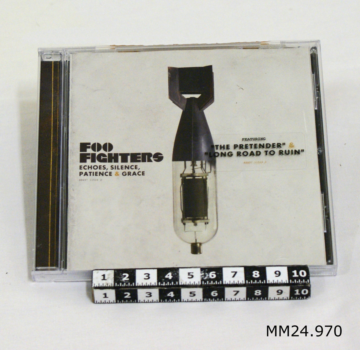 CD-skiva i fodral av plast. Broschyr i vitt med svart text: "Foo fighters, Echoes, Silence, Patience and Grace" samt en bild på en missil. Svart baksida med 12 låtspår i orange.