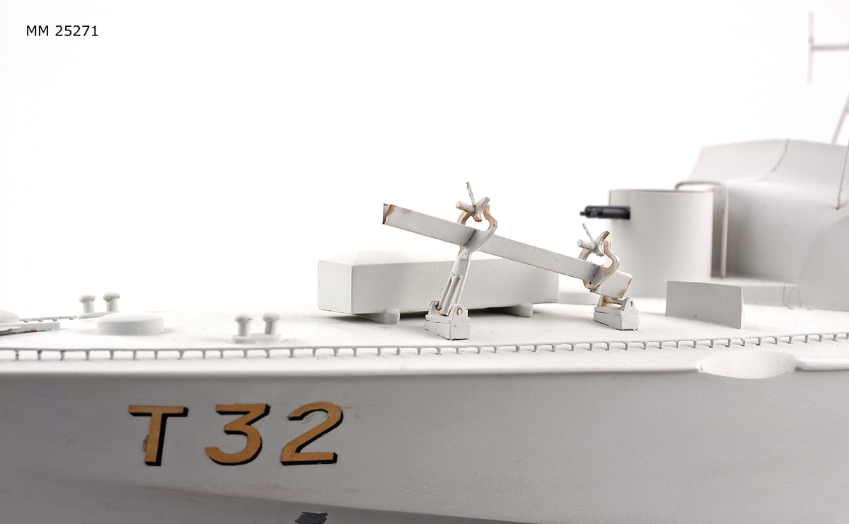 Modell av motortorpedbåten T 32. Från vattenlinjen och neråt målad i svart, från vattenlinjen och uppåt målad i ljusgrått. Märkt på stäven med skuggade bokstäver i guldfärg: "T32". På fördäck står en lysraketkastare och i en upphöjd brunnskonstruktion en dubbel KSP M/36. Mitt på fartyget en brygga med styrratt. På var sida om och bryggans sköldliknande upphöjning sitter en röd och vit frälsarkrans och något akter om dessa dubbellavettage med kulspruta M/36. Akter om bryggan sitter en luftvärnskanon i ett upphöjt brunnslavettage.
Modellen sitter på två konliknande fästen i en glasmonter med svart botten. Dimensioner avser modellen.