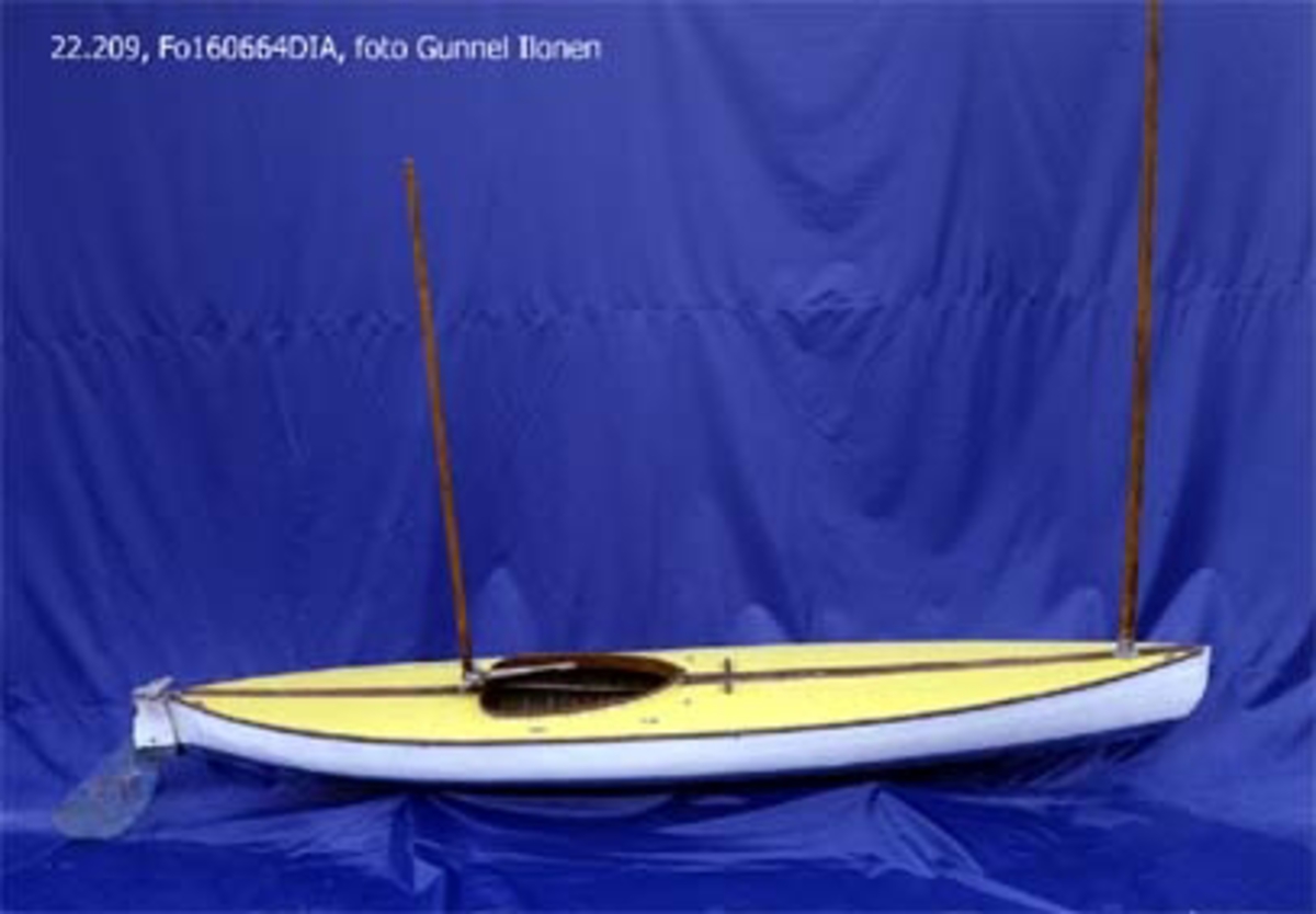 Segelkanot, klass III B, med Güntherrigg och centerbord. Fall, skot och block saknas. Byggd i mahogny, furu och duk. 
Vita fribord och gult däck. Mittfiskar och sarg i mahogny.