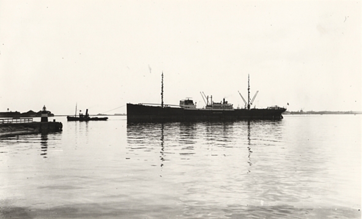 Foto i svartvitt visande lastmotorfartyget "ARIZONA" av Köpenhamn under bogsering i Köpenhamn, troligen 1930-talet.