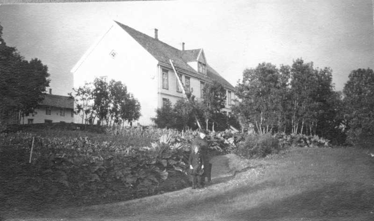 Hovedbygning og hageanlegg ved Melbo Hovedgård sett fra sørvest. Maren Frederiksen og datteren Aase Frederiksen i hagen.