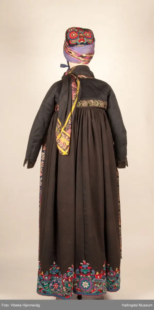 Kone fra Nedre Hallingdal i hallingbunad.  Kona står utstilt i den faste bunadutstillingen på Hallingdal Museum, Nesbyen.  Hallingbunaden består av mange draktdeler; trøye HFN 03608, Forkle HFN 02016, stakk, liv, lue, silketørkle rundt lua, silketørkle rundt halsen HFN 11158, bringduk og skjorte.